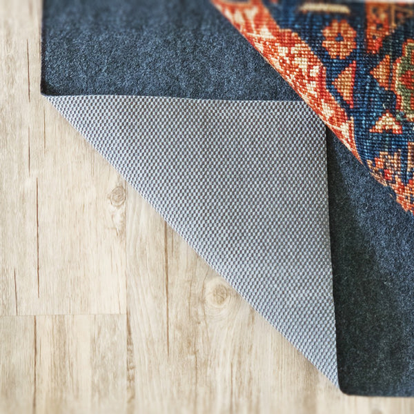 Rug pad corner folded back to show the rubber grip side that stops a rug from sliding