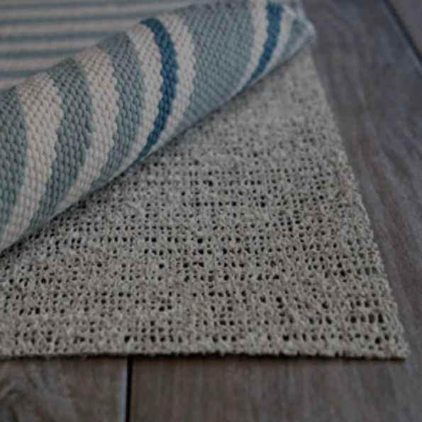 Striped rug rolled back over the open-weave Deluxe rug pad
