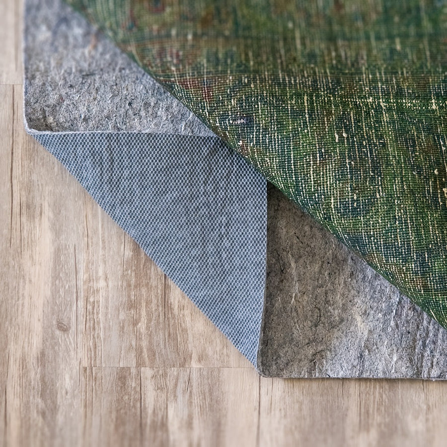 Green rug folded back to show the thick Premium felt rug pad
