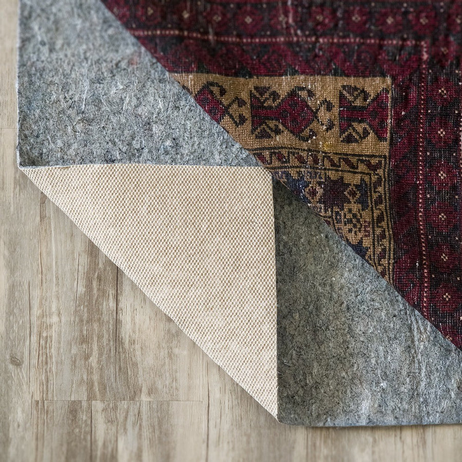 Oriental rug folded back to show the Superior felt rug pad on a wood floor